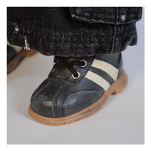 Load image into Gallery viewer, Doll is clothed with black jeans, long sleeve black shirt with short sleeve purple shirt layered over top and black shoes with white side stripes.