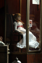 Load image into Gallery viewer, annabelle figure sitting in chair wearing white dress with hair in pig tails. sign reading "warning! positively do not open"