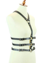 Load image into Gallery viewer, mannequin displaying side of black leather y shaped body harness. shows three adjustable buckles on each side of torso and silver o ring details