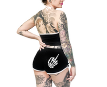 Load image into Gallery viewer, Women&#39;s black shorts with whitetrim and white skeleton hand middle finger design on right buttcheek, white drawstring and white cross bones on front left
