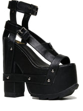 Load image into Gallery viewer, outer view of black vegan leather strappy platform sandal with 6.5" heel. Sandal has gunmetal hardware, adjustable ankle strap and adjustable side strap. Bottom of front platform has a fanned grip for better stability.