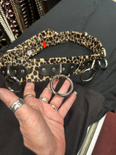 Load image into Gallery viewer, Leopard print belt with metal rings held by a hand on a dark surface
