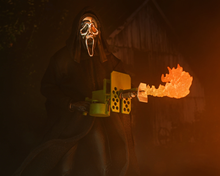 Load image into Gallery viewer, Toy wearing a mask with glowing eyes and mouth, holding a weapon with flames in a dark setting

