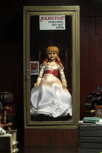 Load image into Gallery viewer, annabelle figure sitting in chair wearing white dress with hair in pig tails. sign reading &quot;warning! positively do not open&quot;
