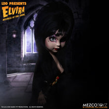 Load image into Gallery viewer, front side view of Elvira Living Dead Doll, with iconic black dress and batty, teased hair, and comes with a dagger that she can store in her waist belt. Stands 10” tall and features 5 points of articulation. Packaged in window box for display.
