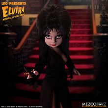 Load image into Gallery viewer, front view of Elvira Living Dead Doll, with iconic black dress and batty, teased hair, and comes with a dagger that she can store in her waist belt. Stands 10” tall and features 5 points of articulation. Packaged in window box for display.
