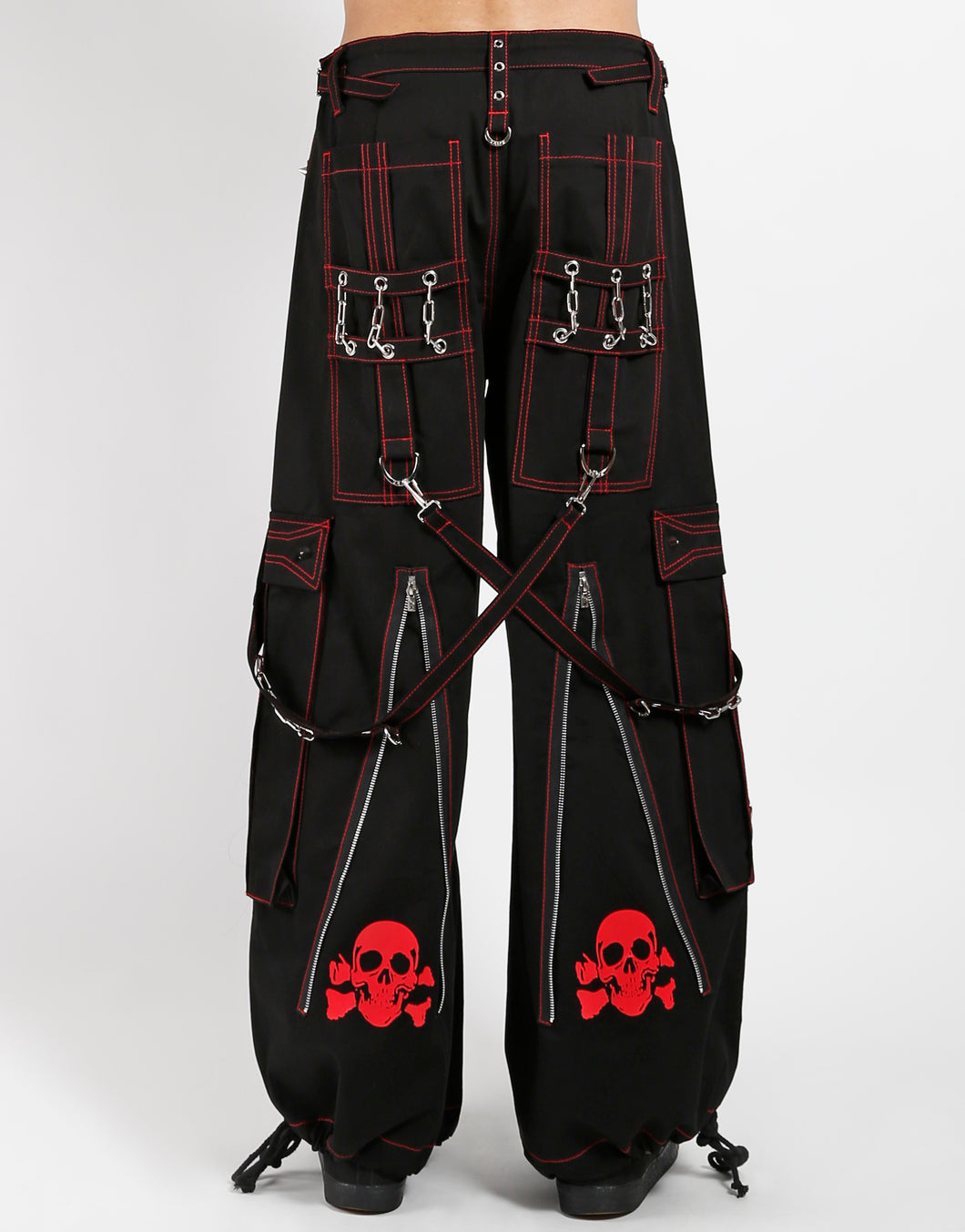 Black classic fit Tripp pants with red stitching, zipper details, removable straps on the back, drawstrings near the feet to tighten the fit, and red skulls printed on the back of each leg.