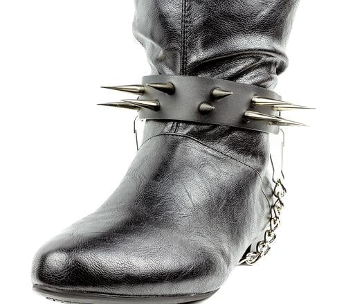 black boot displaying black boot strap  that has two rows of multiple silver sharp pointy spike studs and hanging silver chain 