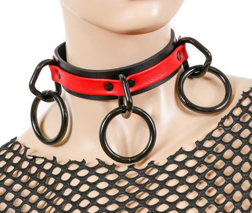 Black and red leather collar with three black D rings and hanging black O rings.