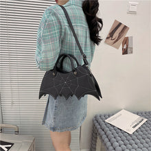 Load image into Gallery viewer, front side of purse showing White stitching spiderweb embroidery on front and hand straps. shown here being worn over the shoulder
