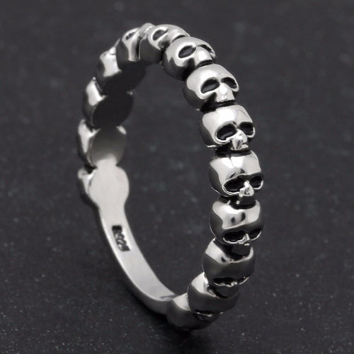 Silver band ring with multi-skull design.