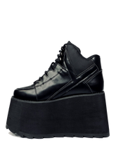 Load image into Gallery viewer, outer view of black vegan leather platform shoe with EVA platform. Shoe looks like a sneaker, but super tall! Shoe has nylon details and mesh lining. Bottom of platform has a &quot;fanned&quot; grip to make the platform more stable.

