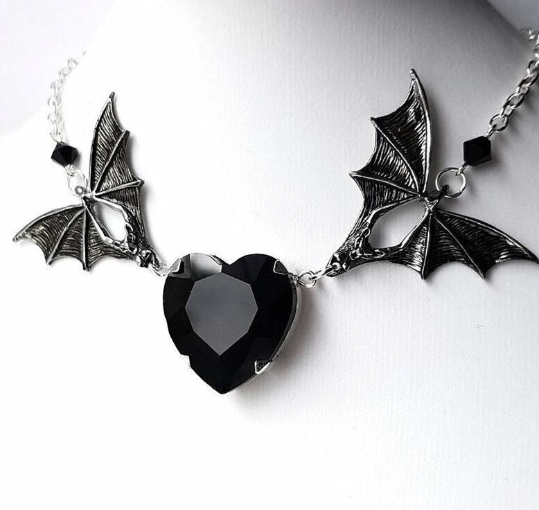 Silver colored zinc alloy bat wing necklace with black heart cubic zirconia gem.