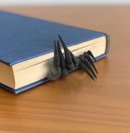 Black devil's claw hands bookmark inside of book