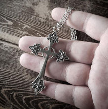 Load image into Gallery viewer, back side of Silver colored zinc alloy vampire cross necklace with red cubic zirconia gem in center of cross.
