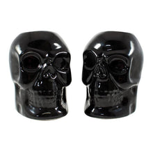 Load image into Gallery viewer, Black skull candlestick holders come in a set of two, and each holds a standard taper candle. CANDLES NOT INCLUDED.
