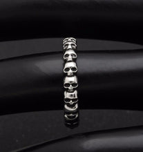 Load image into Gallery viewer, Silver band ring with multi-skull design.
