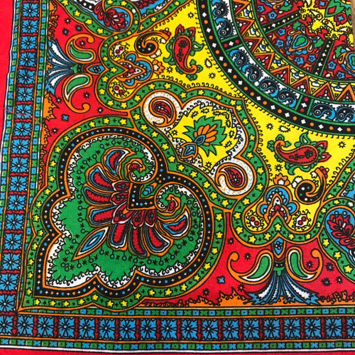 Red bandana with multi-colored green, red, yellow and blue paisley print.