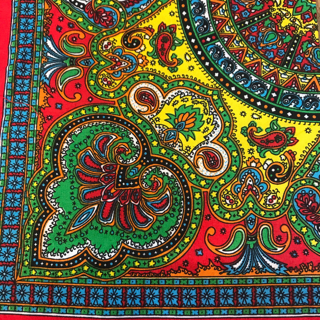 Red bandana with multi-colored green, red, yellow and blue paisley print.