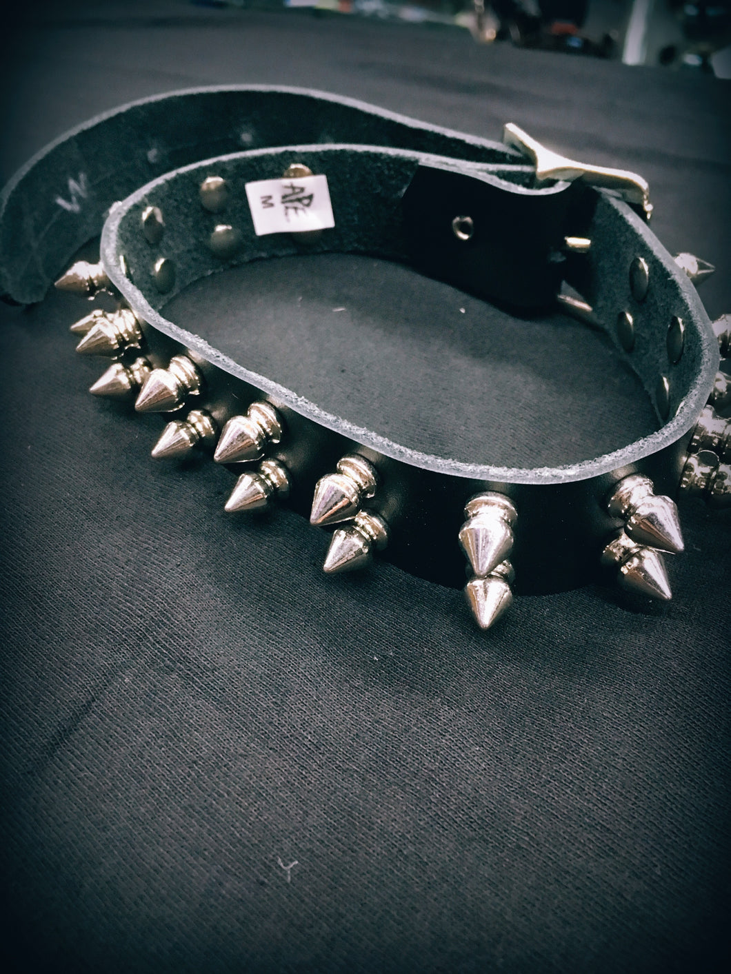 black leather collar with two rows of multiple silver tree spikes. shows belt closure