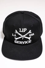 Load image into Gallery viewer, front view of Black hat with white embroidery that reads &quot;LIP SERVICE LA USA&quot; on the front with crossbones. Snaps on the back.
