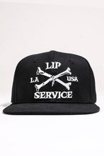 Load image into Gallery viewer, front view of Black hat with white embroidery that reads &quot;LIP SERVICE LA USA&quot; on the front with crossbones. Snaps on the back.
