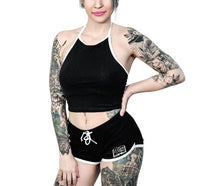 Load image into Gallery viewer, Black shorts with white trim and white planchette rose design on both buttcheeks, white drawstring and white spell book design on front left
