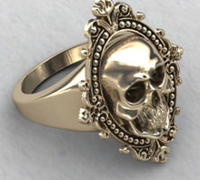 Load image into Gallery viewer, Gold colored zinc alloy skull ring with pretty oval detailed frame around skull.
